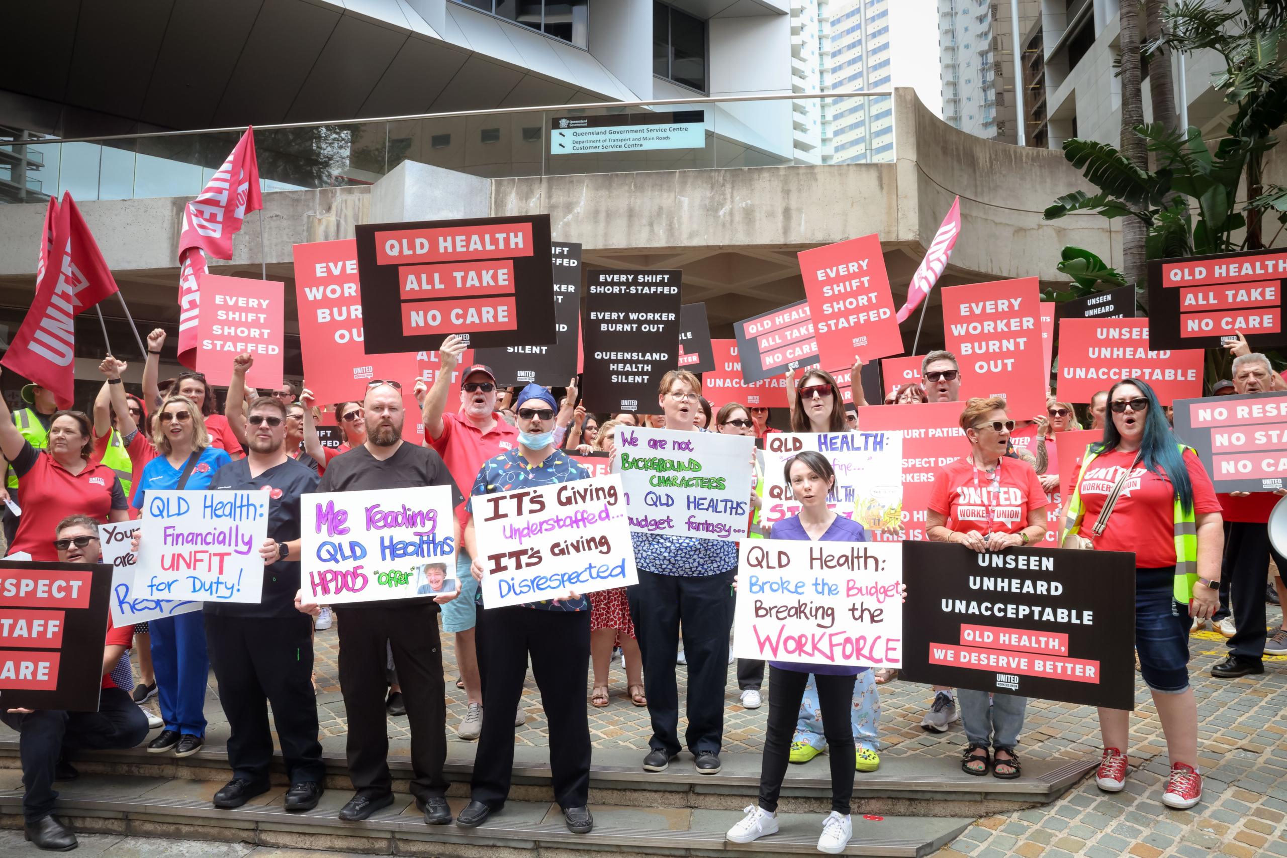 A group of health workers and UWU members protesting outside a building.